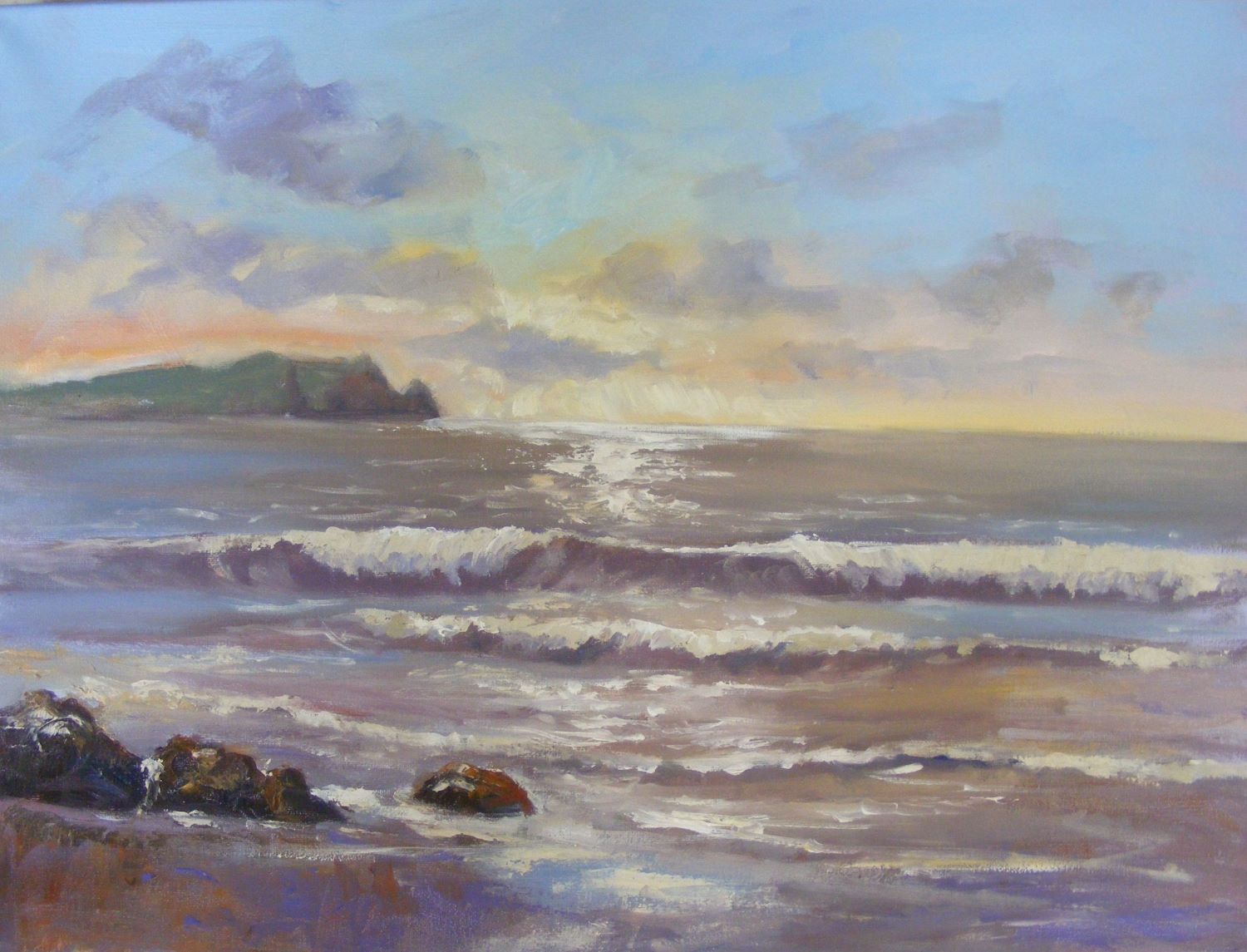 incoming surf breaking onto sand with  distant cliffs